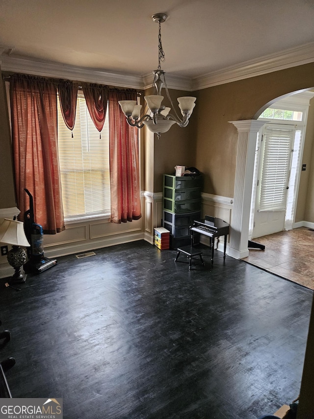 dining area featuring arched walkways, crown molding, wood finished floors, baseboards, and an inviting chandelier