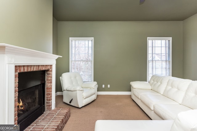 living area with a brick fireplace, a healthy amount of sunlight, baseboards, and carpet flooring