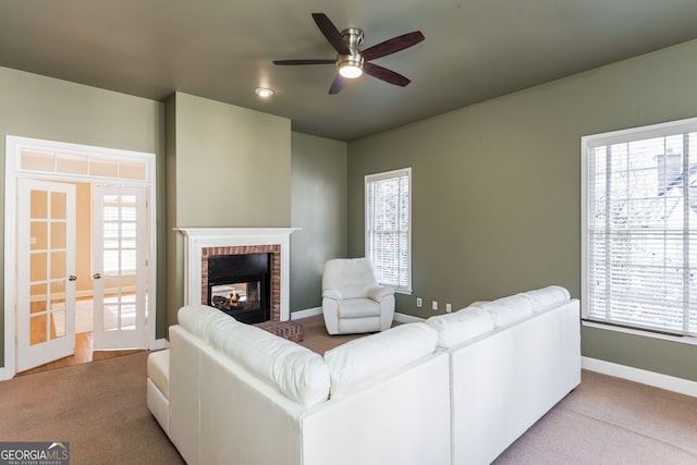 living room with carpet floors, a wealth of natural light, a brick fireplace, and baseboards