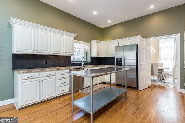 kitchen with tasteful backsplash, recessed lighting, appliances with stainless steel finishes, white cabinetry, and light wood-type flooring