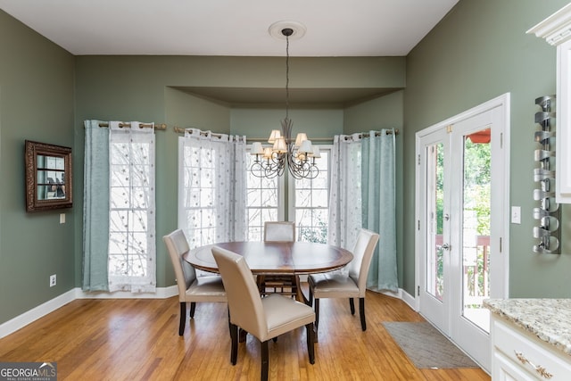 dining space with a chandelier, light wood-style flooring, and baseboards