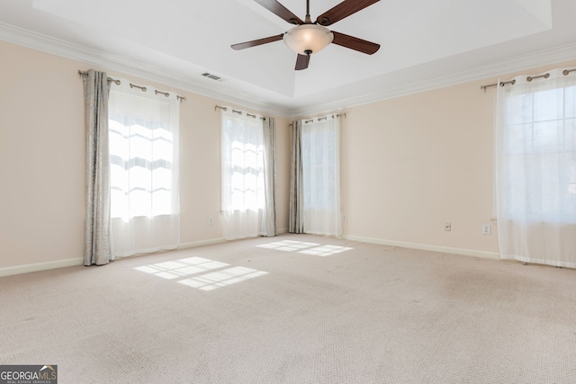 empty room featuring ornamental molding, a raised ceiling, visible vents, and light colored carpet