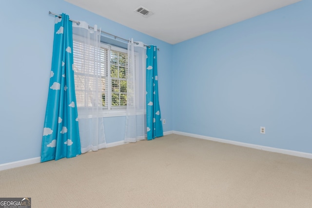 unfurnished room with carpet floors, visible vents, and baseboards