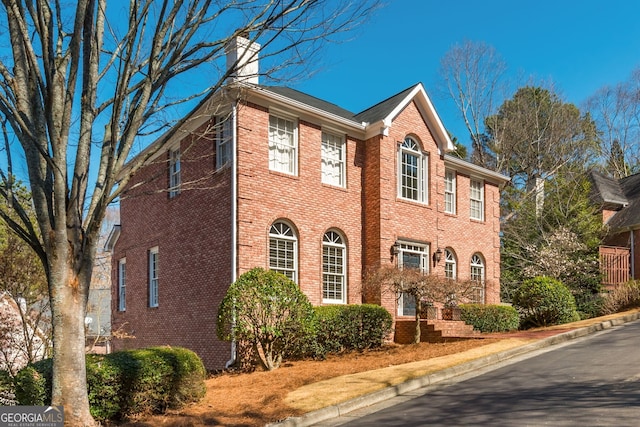 view of front of house with brick siding and a chimney