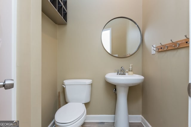 bathroom with a sink, toilet, and baseboards