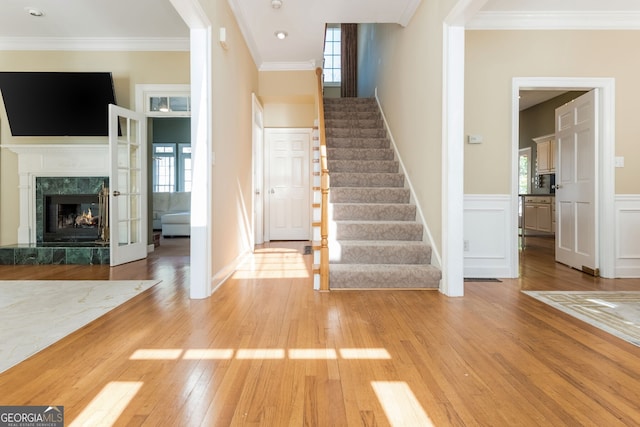 foyer with light wood-style floors, plenty of natural light, a fireplace, and crown molding