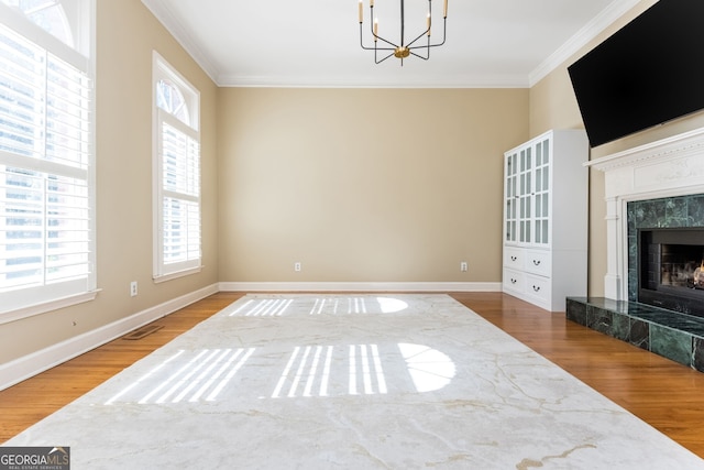 living area featuring baseboards, visible vents, wood finished floors, crown molding, and a fireplace