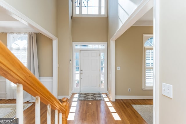 foyer with a healthy amount of sunlight, stairway, baseboards, and wood finished floors