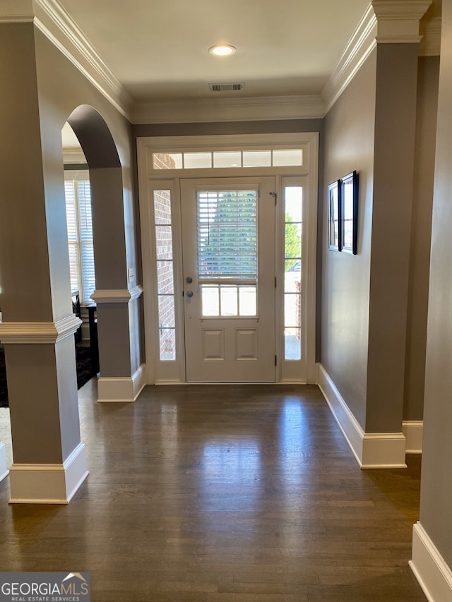 foyer entrance featuring dark wood-type flooring, arched walkways, and crown molding