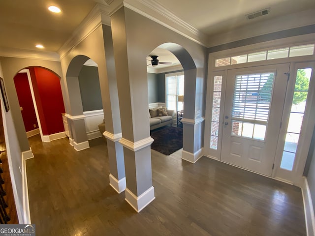 entryway with arched walkways, dark wood-style floors, visible vents, and crown molding