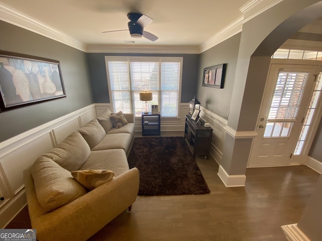 living room with a healthy amount of sunlight, arched walkways, and ornamental molding