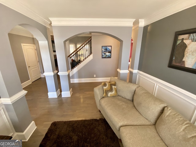 living area featuring arched walkways, stairway, wood finished floors, and crown molding