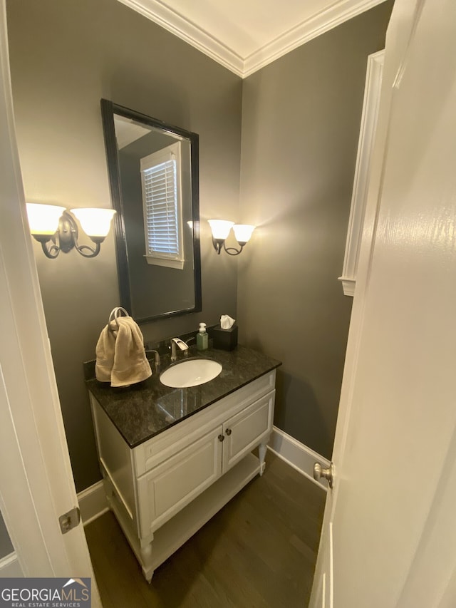 bathroom featuring baseboards, wood finished floors, vanity, and crown molding