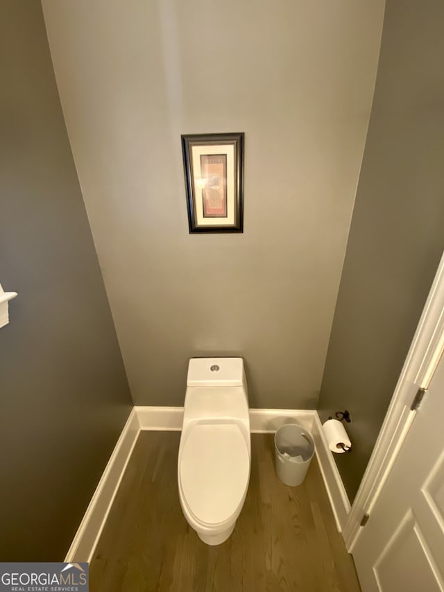 bathroom with wood finished floors, toilet, and baseboards