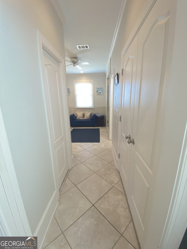 corridor featuring light tile patterned floors, visible vents, and ornamental molding