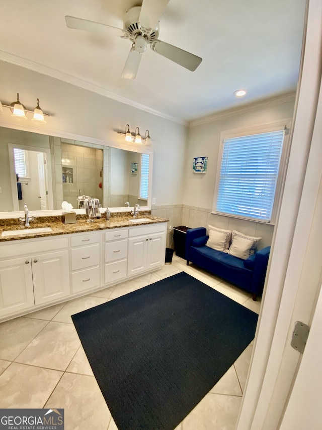 bathroom featuring crown molding, a sink, a tile shower, and tile patterned floors