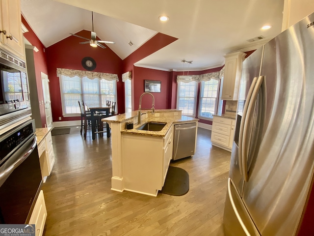 kitchen featuring light wood-style flooring, a center island with sink, appliances with stainless steel finishes, and a sink