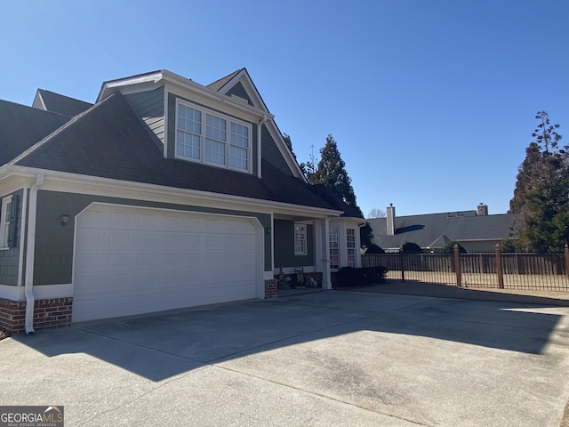 view of front of property featuring a garage, concrete driveway, and fence