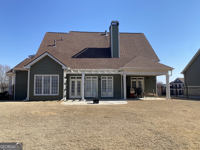 rear view of house with a patio, fence, french doors, roof with shingles, and a chimney