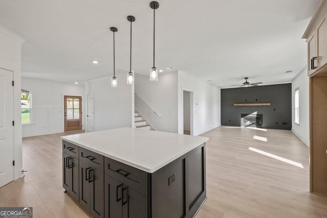 kitchen with open floor plan, light wood finished floors, a fireplace, and pendant lighting