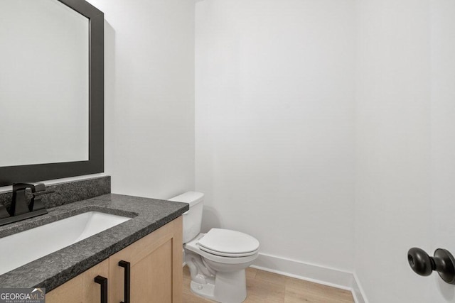 bathroom with vanity, toilet, and baseboards