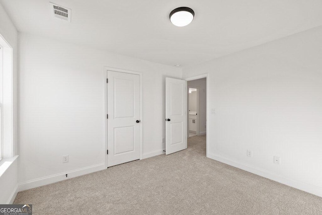 unfurnished bedroom with carpet, visible vents, and baseboards