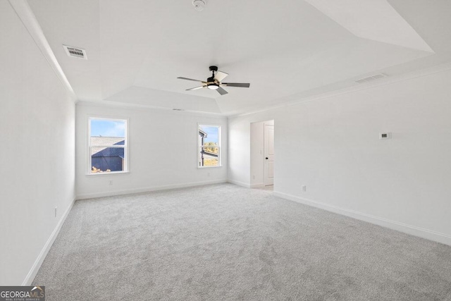 empty room featuring a raised ceiling, visible vents, baseboards, and carpet flooring