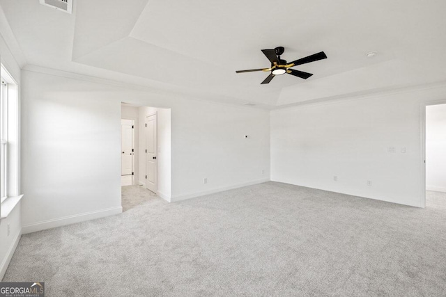 empty room featuring a raised ceiling, light colored carpet, visible vents, ornamental molding, and ceiling fan