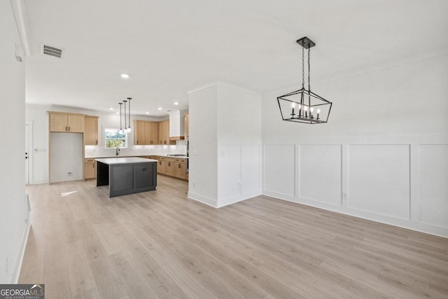 kitchen with a kitchen island, visible vents, a decorative wall, and light wood-style flooring