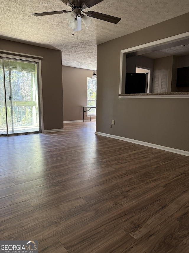 empty room with a textured ceiling, wood finished floors, and baseboards