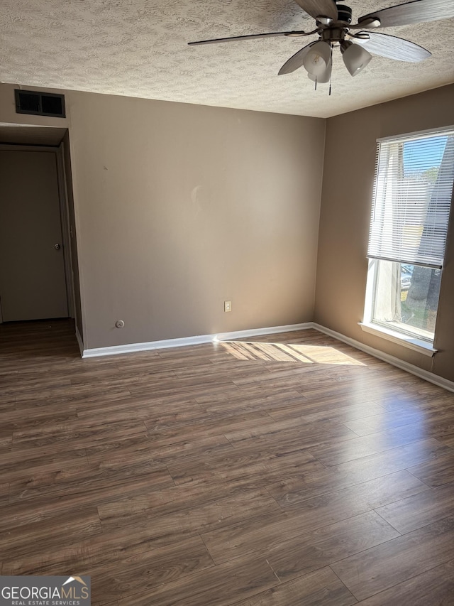 unfurnished room with dark wood-style floors, visible vents, a textured ceiling, and baseboards