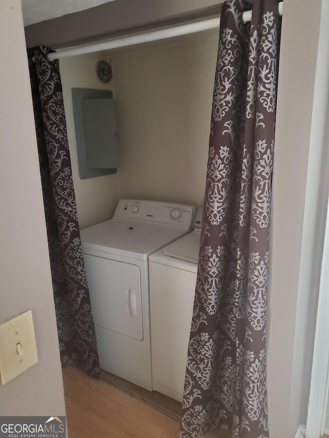 laundry area with laundry area, light wood-style flooring, electric panel, and independent washer and dryer