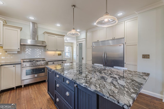 kitchen with high end appliances, dark wood finished floors, wall chimney exhaust hood, and ornamental molding