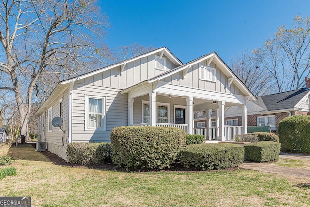 view of front facade with board and batten siding, covered porch, a front lawn, and a ceiling fan