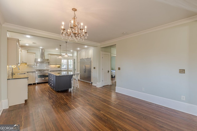 kitchen featuring a kitchen island, a sink, wall chimney range hood, backsplash, and high end appliances