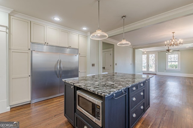 kitchen featuring decorative light fixtures, ornamental molding, dark wood-style flooring, and built in appliances