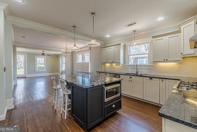 kitchen with crown molding, backsplash, stainless steel appliances, baseboards, and dark wood-style floors