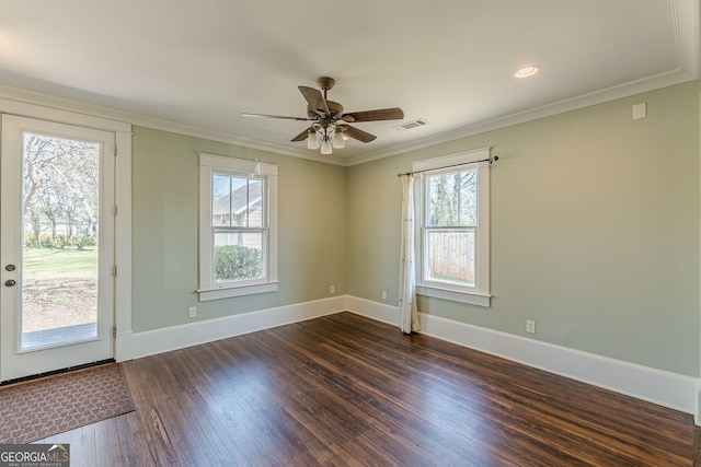 empty room with ornamental molding, baseboards, dark wood-style floors, and visible vents
