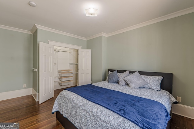 bedroom with crown molding, a spacious closet, wood finished floors, and baseboards