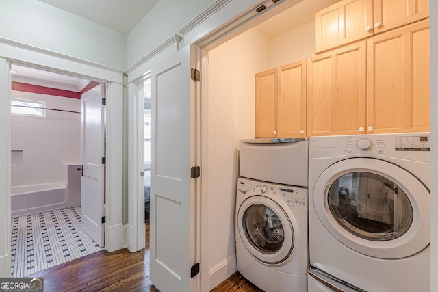 laundry area featuring separate washer and dryer, dark wood-type flooring, cabinet space, and baseboards