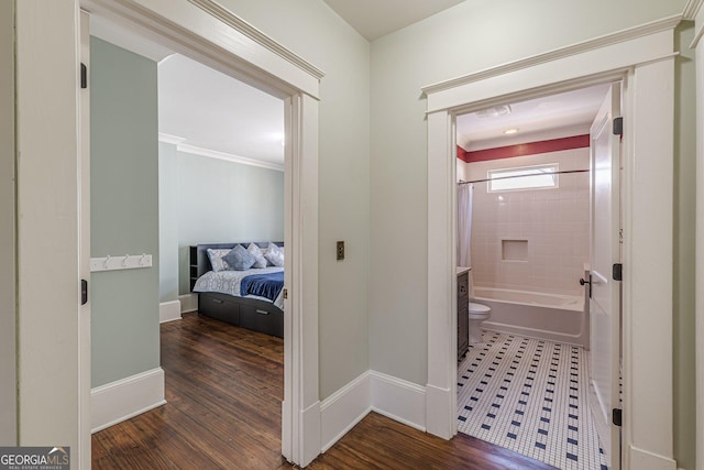 corridor with wood finished floors, baseboards, and ornamental molding