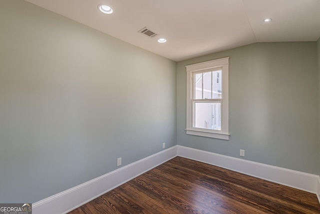 empty room featuring baseboards, visible vents, dark wood-style flooring, vaulted ceiling, and recessed lighting