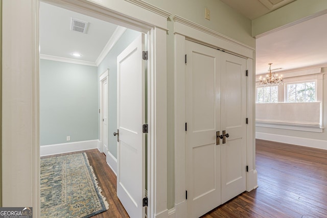 corridor featuring dark wood-style floors, baseboards, visible vents, and ornamental molding