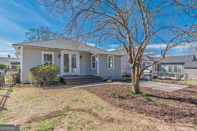 rear view of property featuring a patio, french doors, fence, and roof with shingles