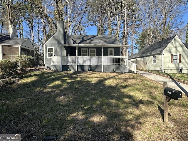 ranch-style home with a porch, a front yard, and a chimney