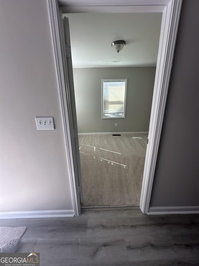 corridor with visible vents, baseboards, and wood finished floors