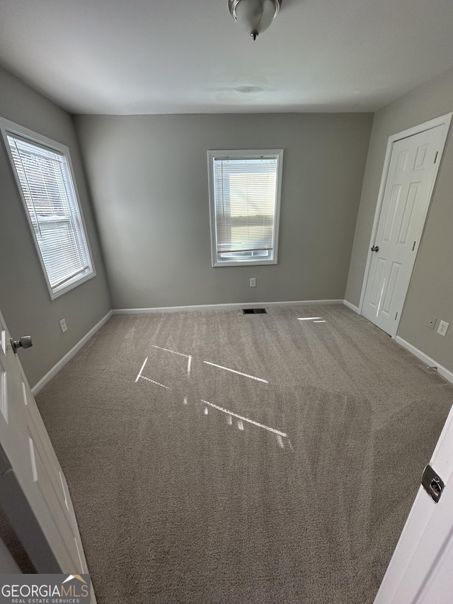 carpeted spare room featuring visible vents and baseboards