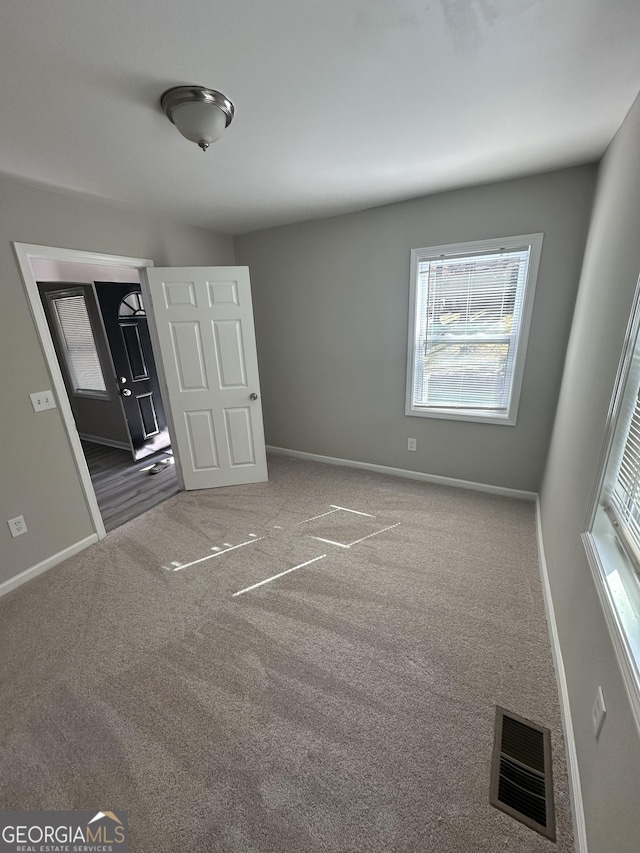 unfurnished bedroom with carpet flooring, visible vents, and baseboards