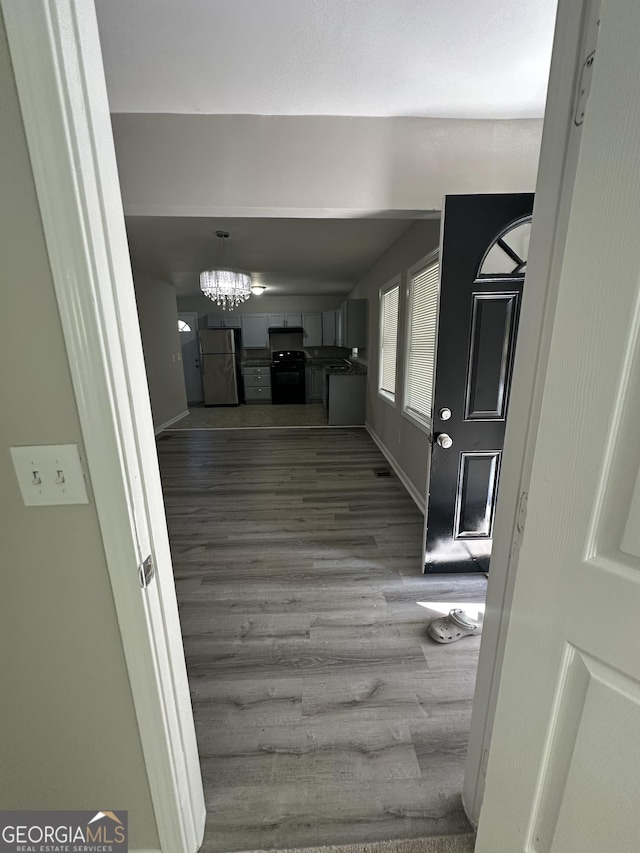 hall with a chandelier, baseboards, and wood finished floors