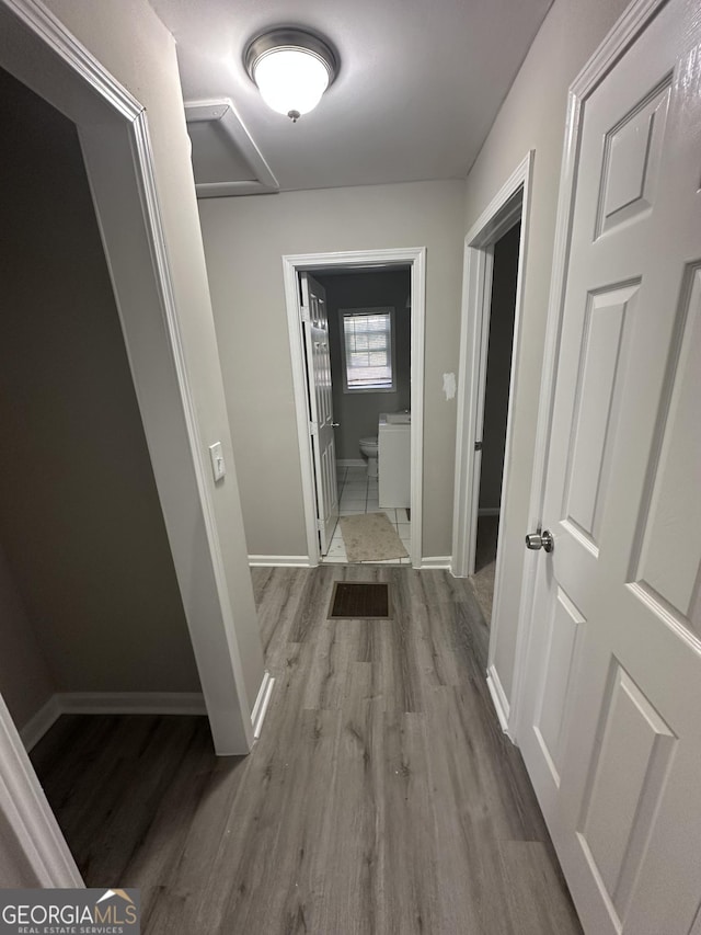 hall with visible vents, baseboards, and wood finished floors